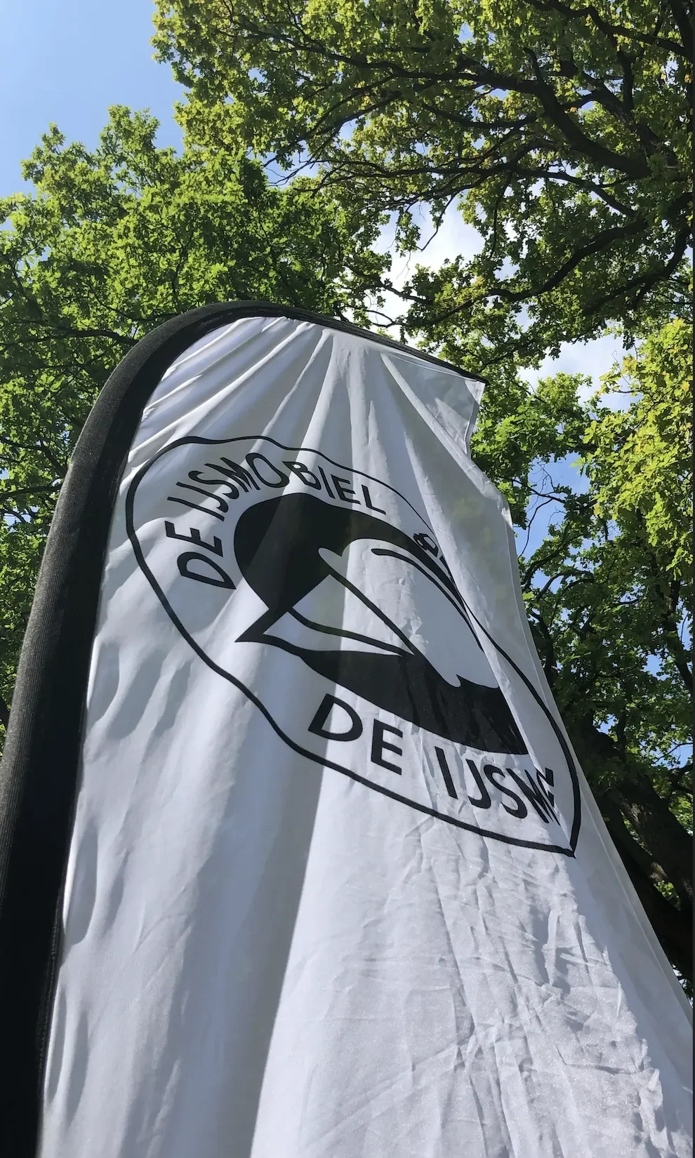 Grote vlag van De IJsmobiel die naast de ijskar staat op locaties