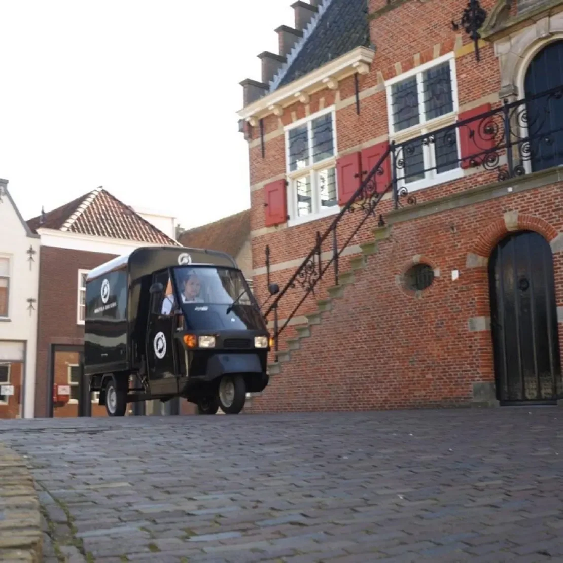 Ijskar tuk tuk komt aanrijden door de stad over een oude brug