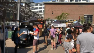 Mensen bij de ijskar van De IJsmobiel op een stadslocatie in de zomer
